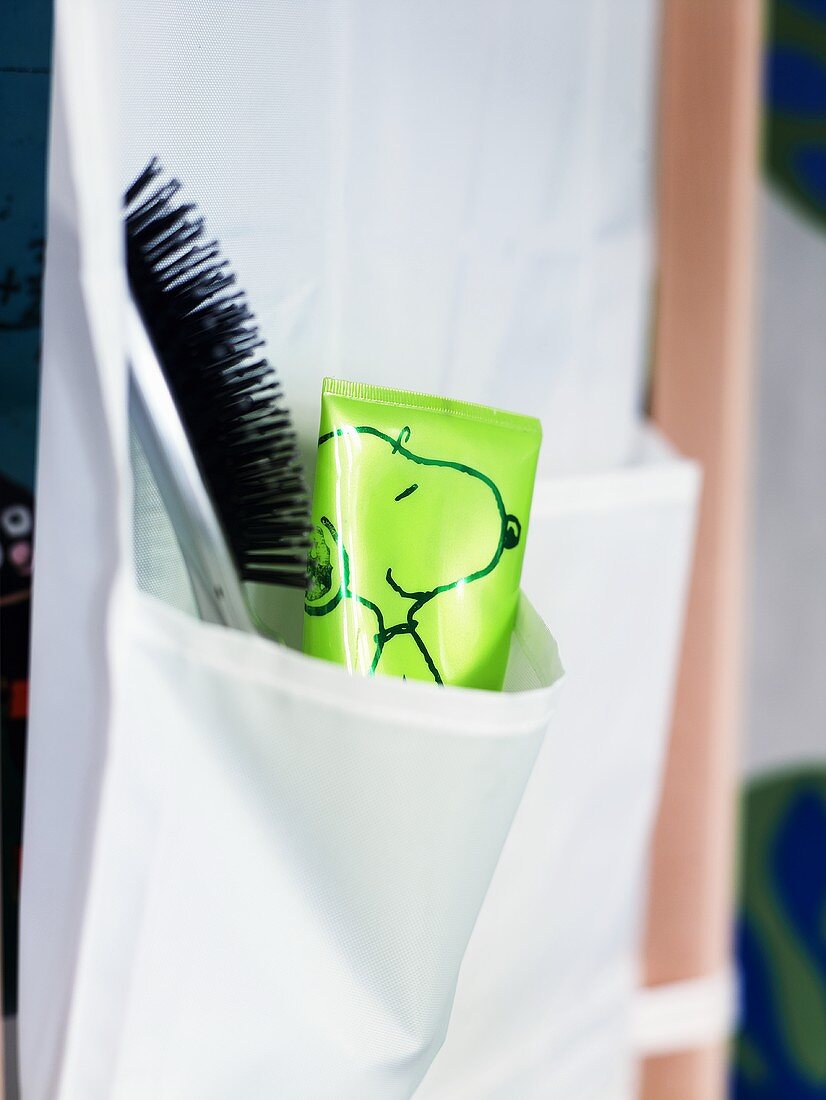 A brush and a tube in a hanging fabric bag