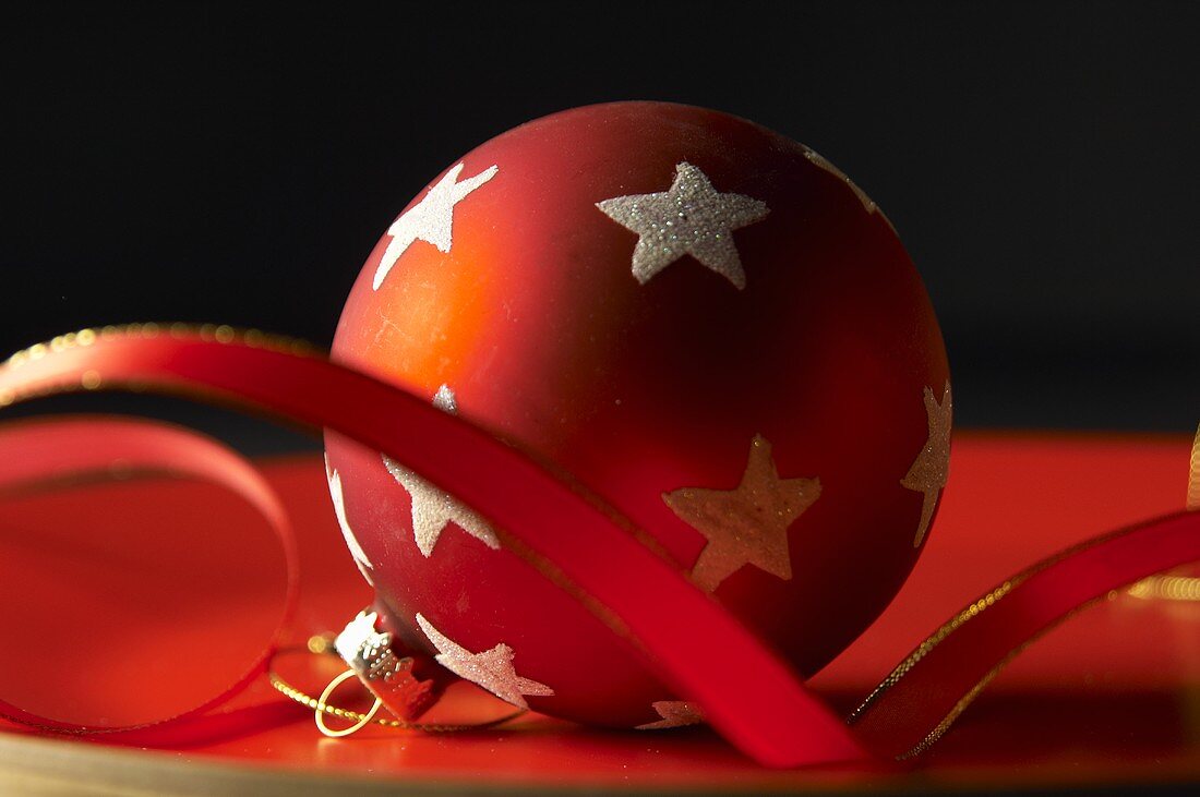 Rote Christbaumkugel mit weissen Sternen und Band