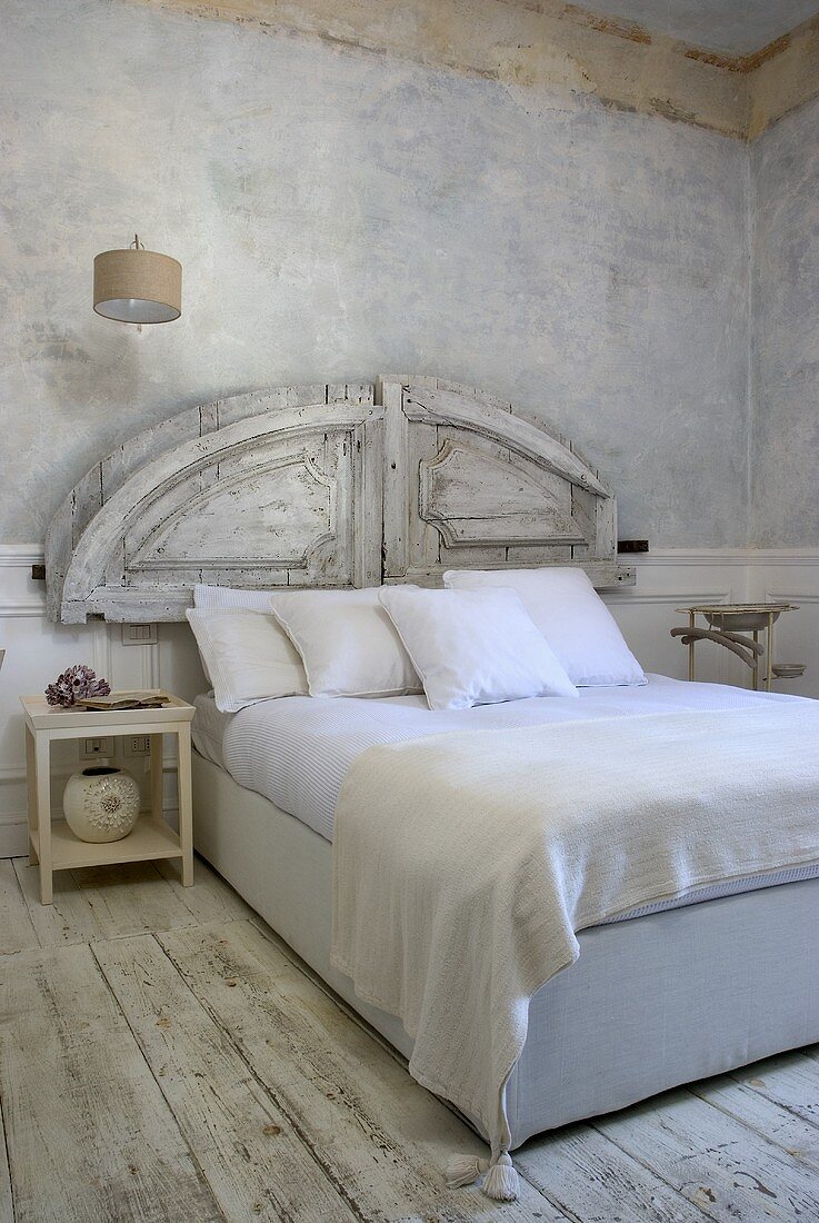 A modern double bed with a rustic headboard and white bedclothes