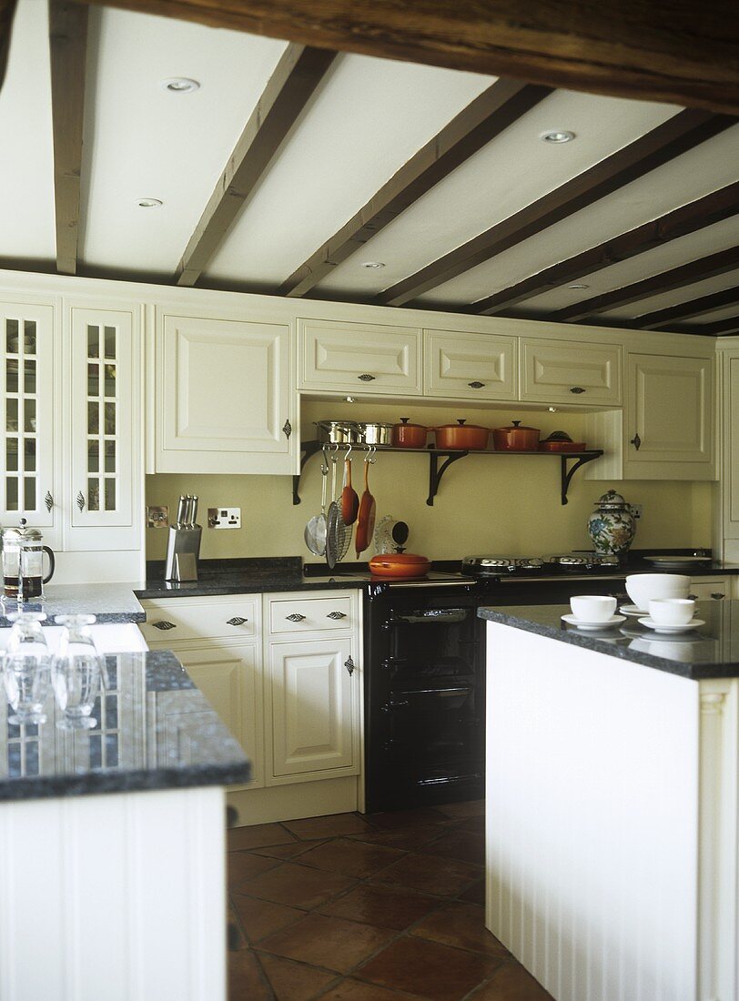 Fitted kitchen and island unit with granite worktops, utensils and crockery.