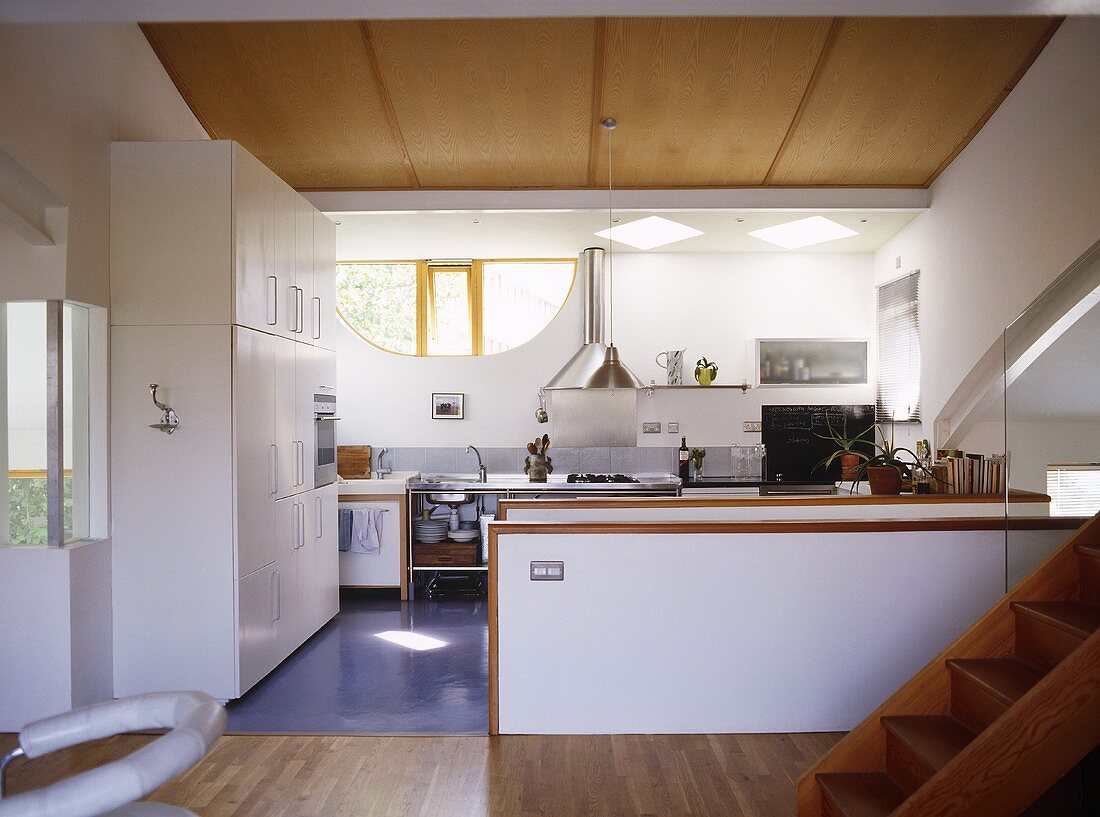 White kitchen area, stairs leading to another room and wooden flooring