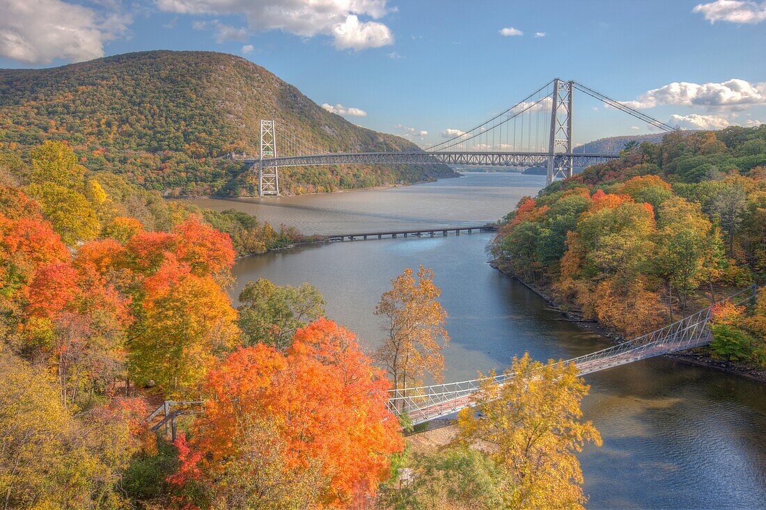Autumn view of Bear Mountain Bridge in the distance with the CSX railroad bridge and the Popolopen Creek Suspension Footbridge in the foreground, Fort Montgomery, New York, USA