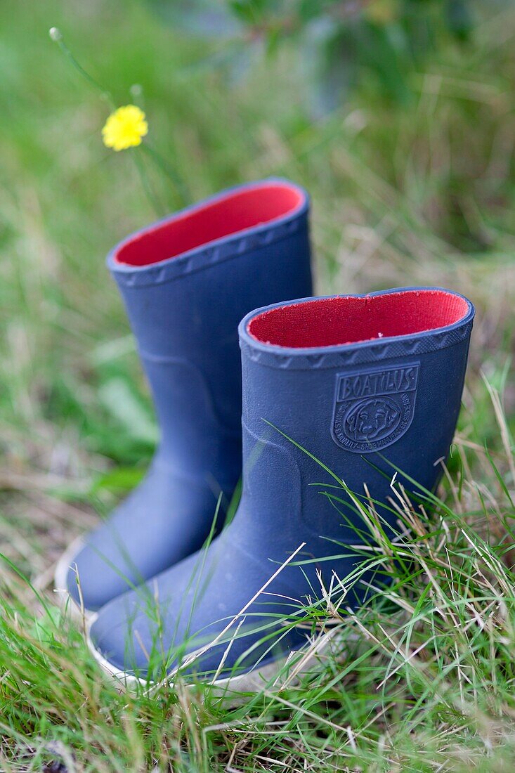 Blue rain boots of a child placed in the grass