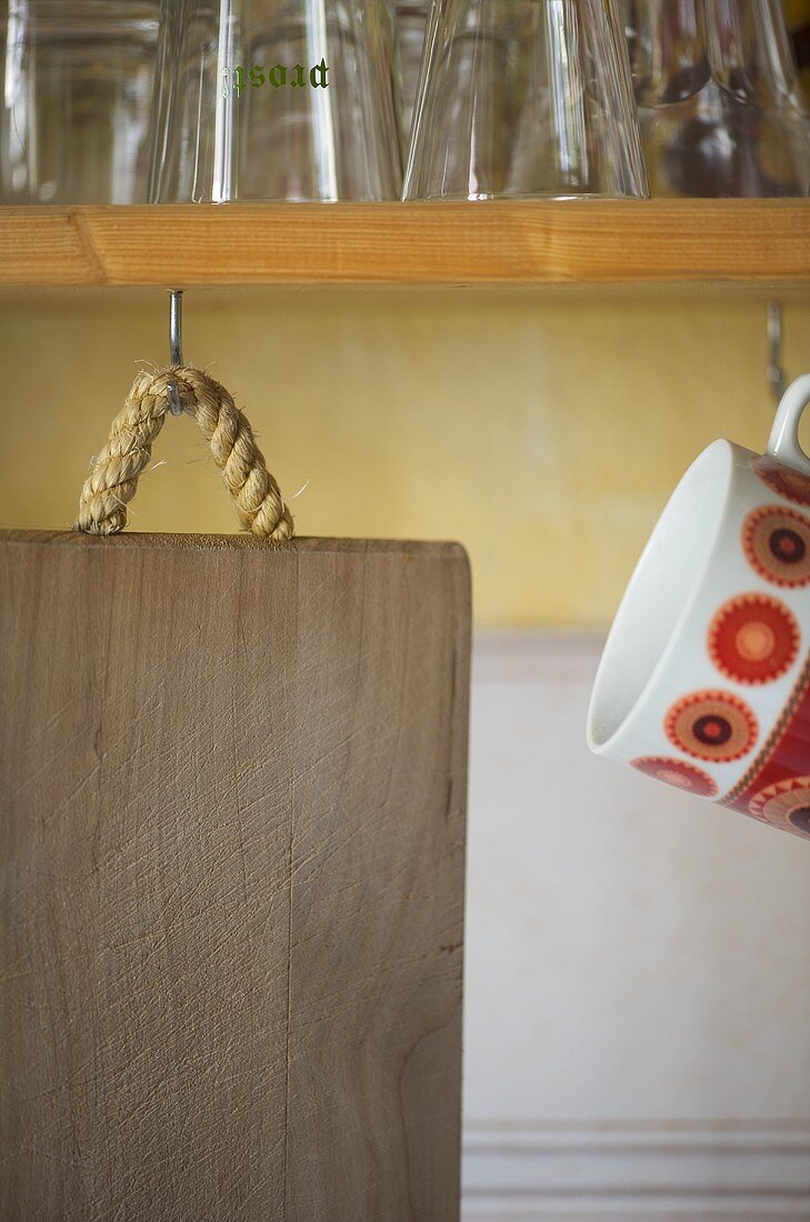 Wooden chopping board hanging from hook in shelf