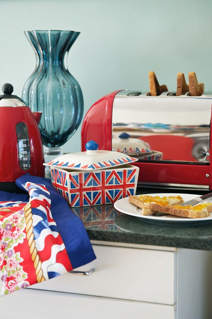 Keramikdose mit Englandflagge neben Frühstück und roter Vintage Toaster