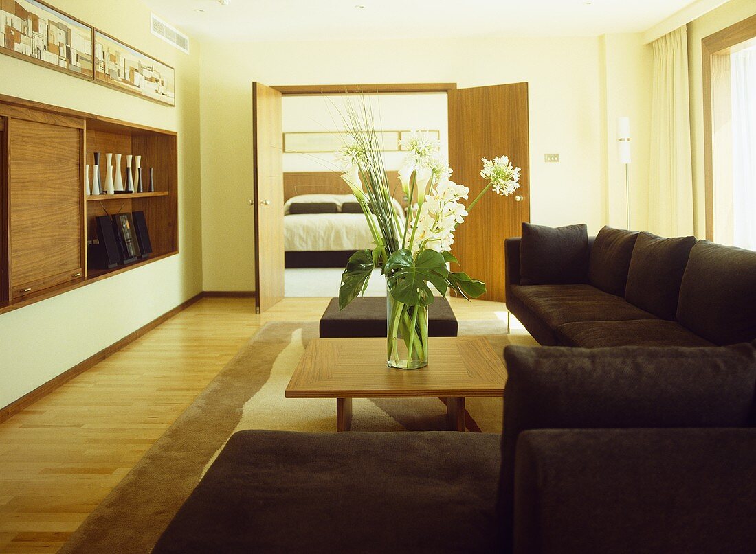 White flower arrangement on coffee table surrounded by upholstered sofas