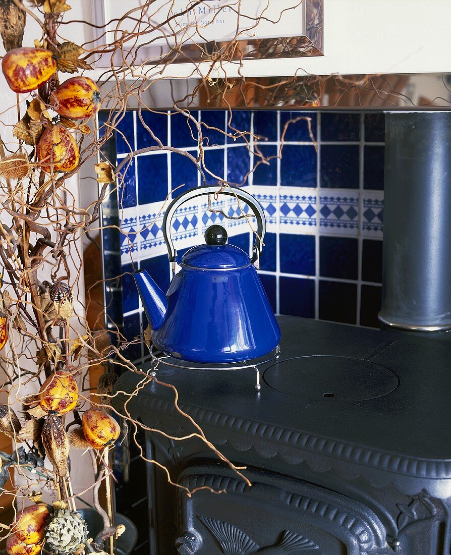 Blue tea kettle (retro design) in a cast-iron wood burning stove