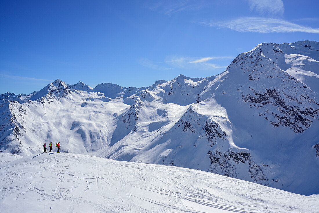 Three persons back-country skiing looking towards Stubai Alps, Schneespitze, valley of Pflersch, Stubai Alps, South Tyrol, Italy