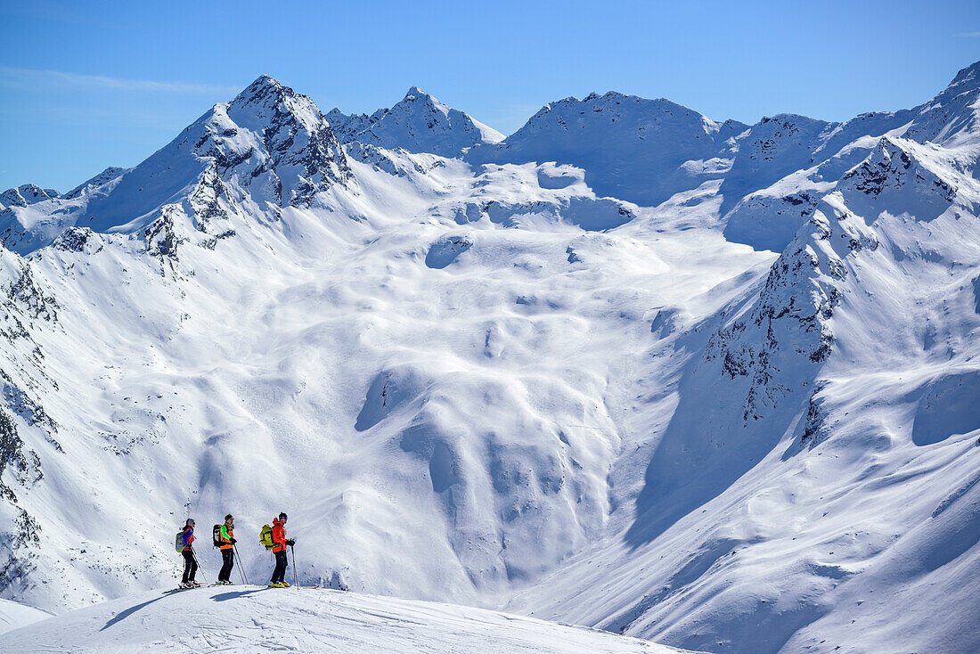 Three persons back-country skiing looking towards Stubai Alps, Schneespitze, valley of Pflersch, Stubai Alps, South Tyrol, Italy