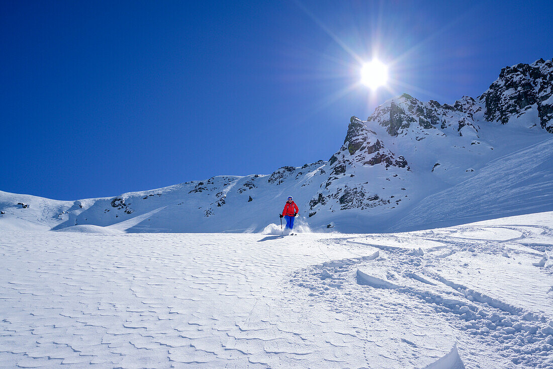 Frau auf Skitour fährt durch Pulverschnee vom Passo Croce ab, Passo Croce, Valle Maira, Cottische Alpen, Piemont, Italien