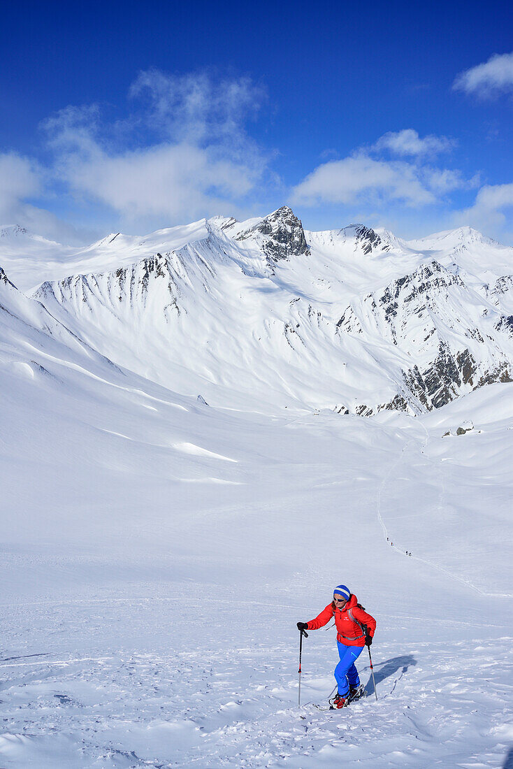 Woman back-country skiing ascending towards Monte Faraut, Pelvo di Ciabiera in the background, Monte Faraut, Valle Varaita, Cottian Alps, Piedmont, Italy