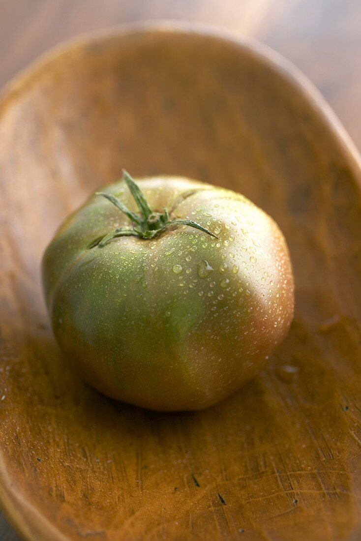 Heirloom Tomate mit Wassertropfen in Holzschale