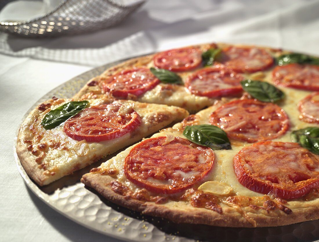 Pizza mit Tomaten und Basilikum, angeschnitten