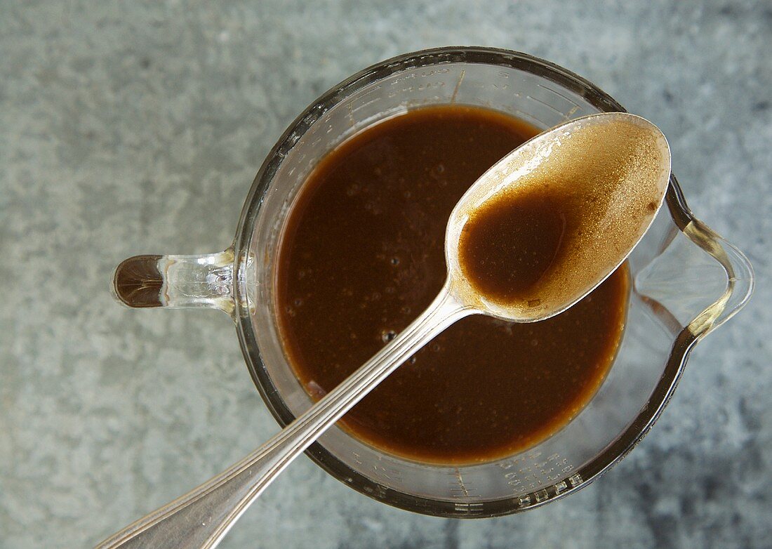 Spoon With Balsamic Vinaigrette Resting on Pitcher of Vinaigrette