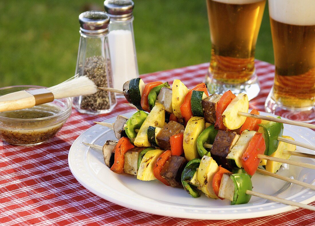 Grilled Kabobs Piled on a Plate; On an Outdoor Table; Beer