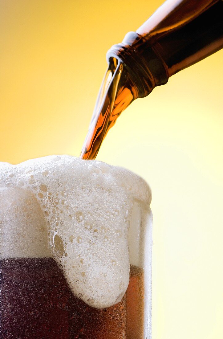 Pouring Beer From Bottle into Overflowing Glass