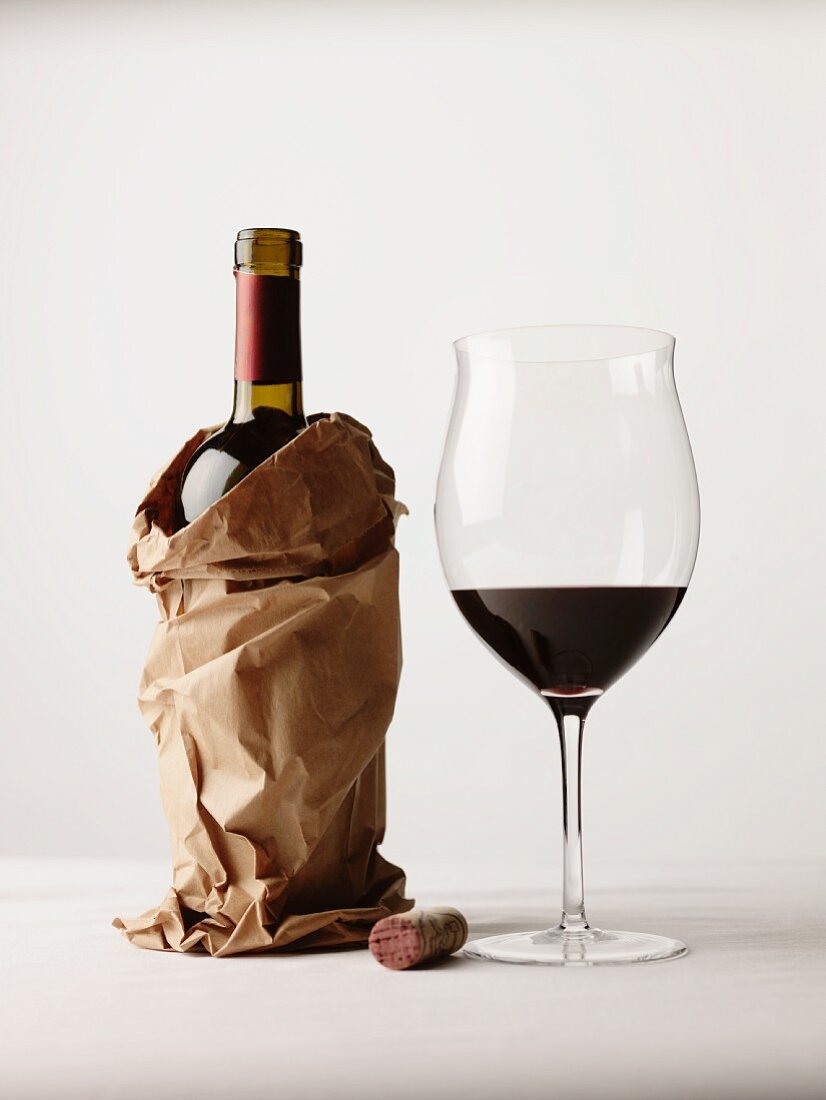 Bottle of Red Wine in a Brown Paper Bag; Glass of Red Wine