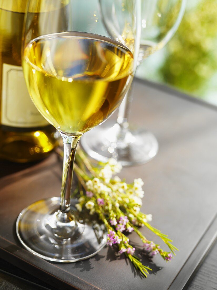 Glass of White Wine with Wine Bottle and Flowers; On Table