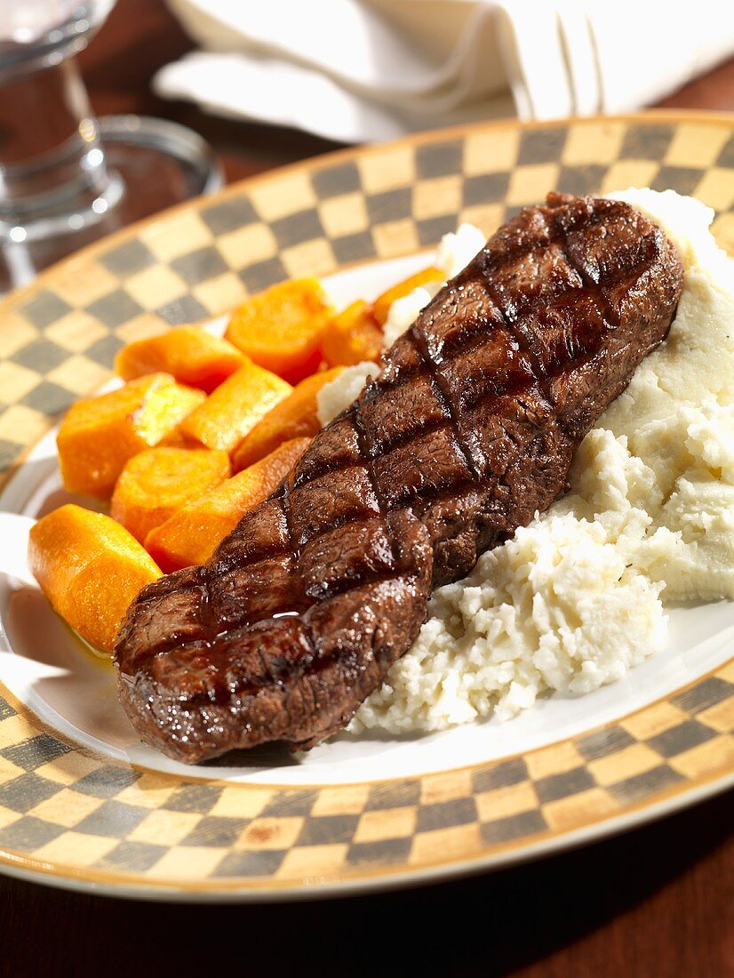 Grilled Steak Over Mashed Potatoes with Sliced Carrots