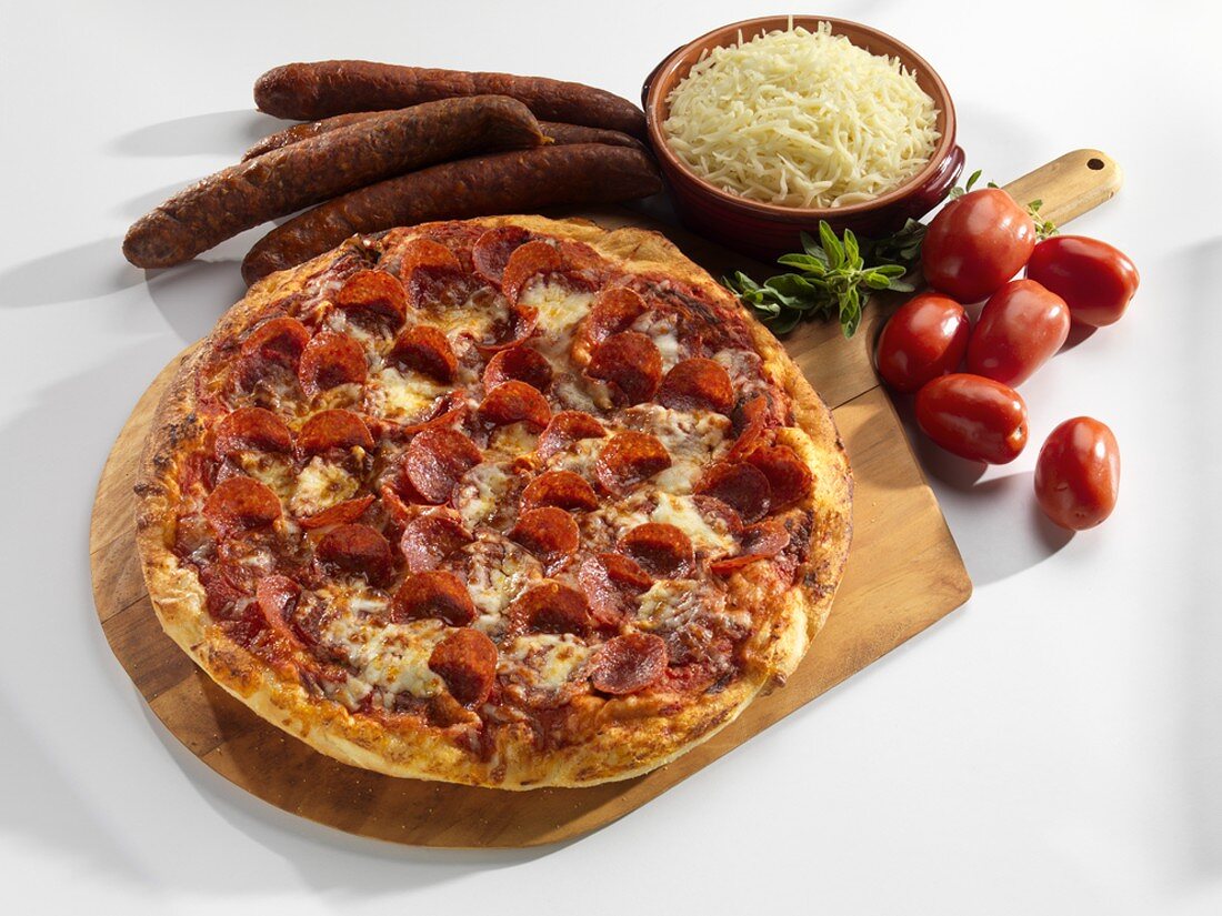 Pizza mit Peperoniwurst, umgeben von Zutaten