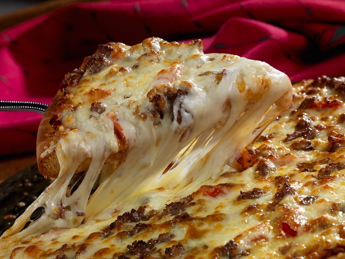 Stück rustikale Pizza mit Wurst und Käse auf Heber