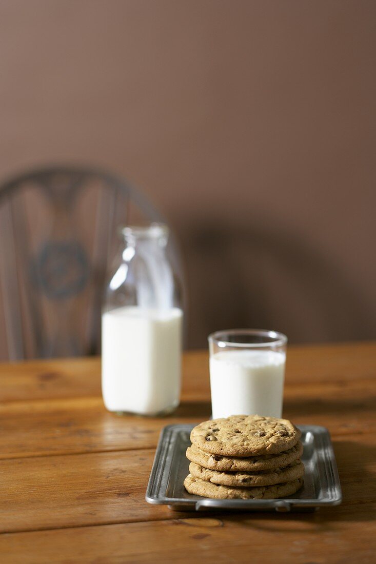 Stack of Chocolate Chip Cookies with Glass of Milk, Bottle of Milk on Table