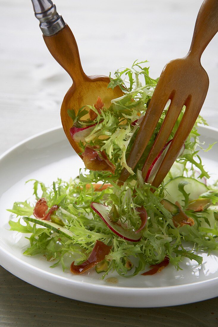 Placing Mesclun Salad on a Plate with Wooden Salad Servers