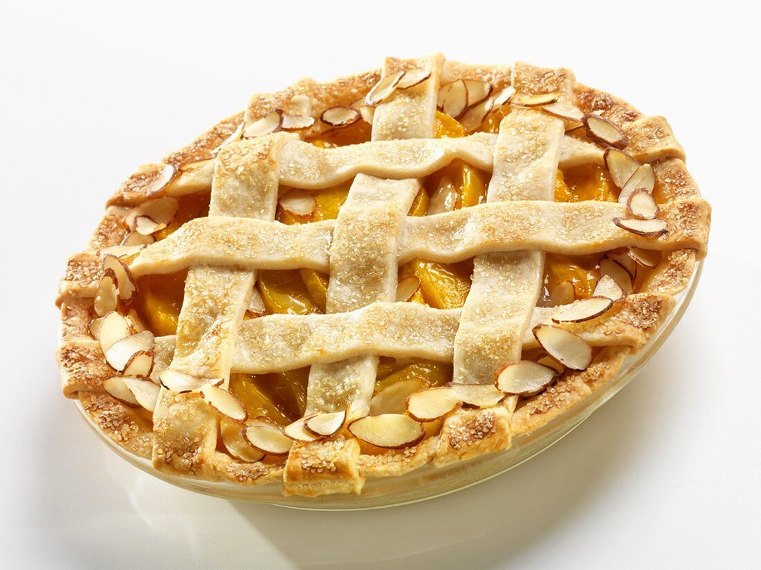 Whole Peach Almond Pie with a Lattice Top on a White Background