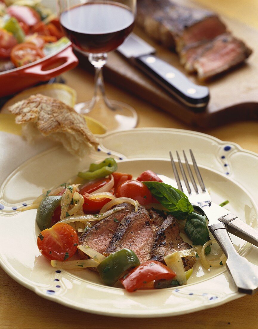 Sliced Steak with Vegetables on a Plate with Crusty Bread and Red Wine
