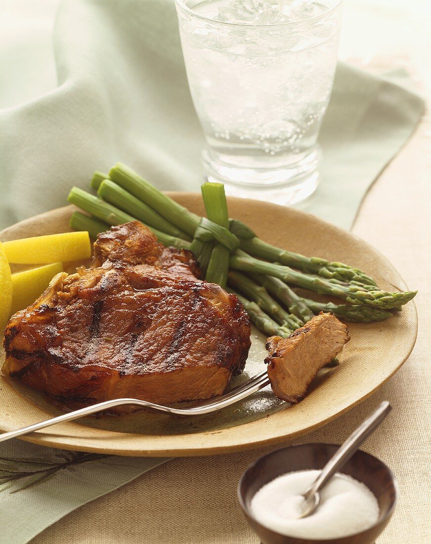 Grilled Pork Chop with Piece on a Fork, Asparagus, On a Plate