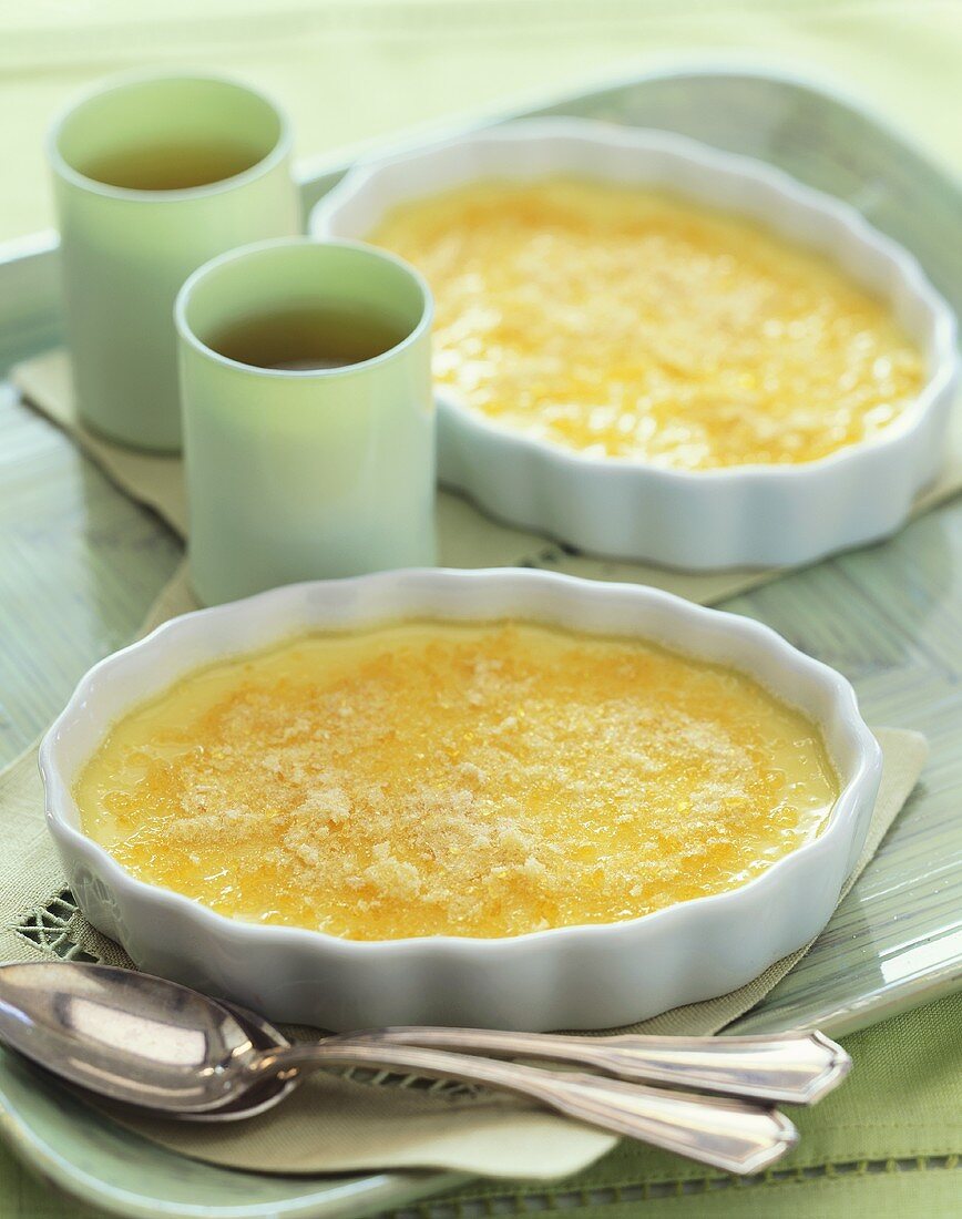 Two Servings of Crème Brulee with Two Cups of Tea on a Tray