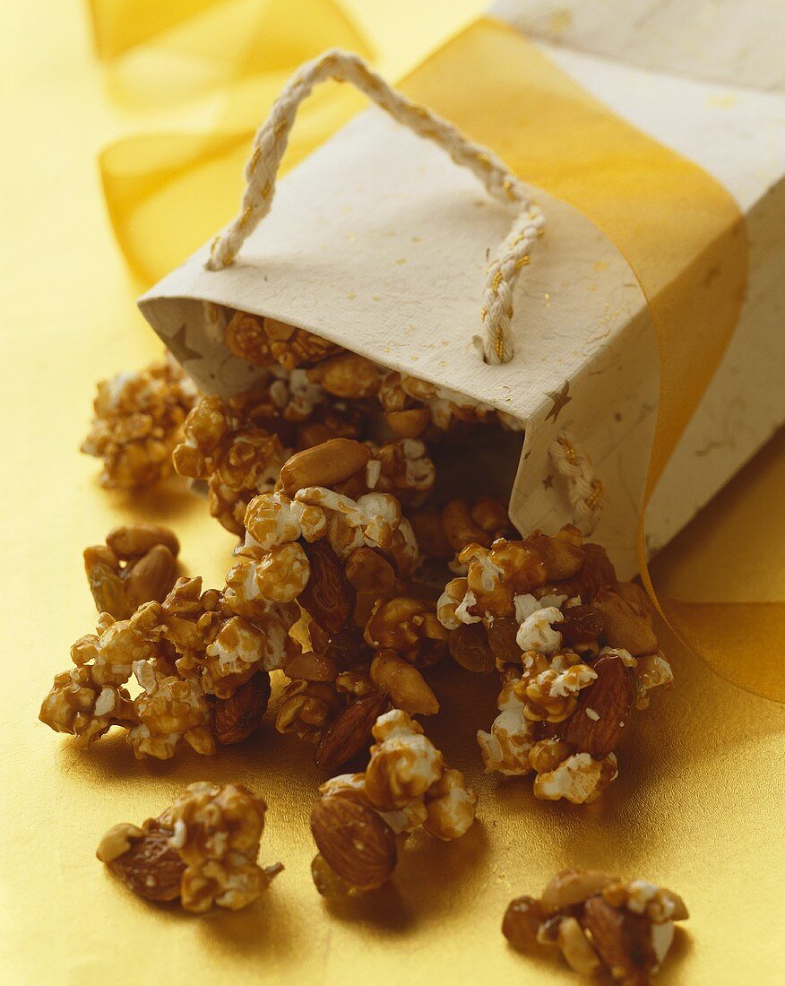 Karamellisiertes Nuss-Popcorn fällt aus umgekippter Papiertüte