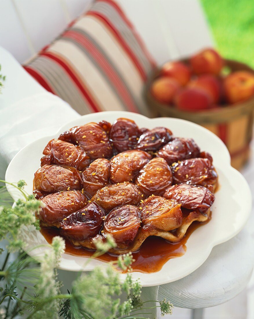 Ganze Tarte Tatin mit Pfirsichen auf Gartenstuhl