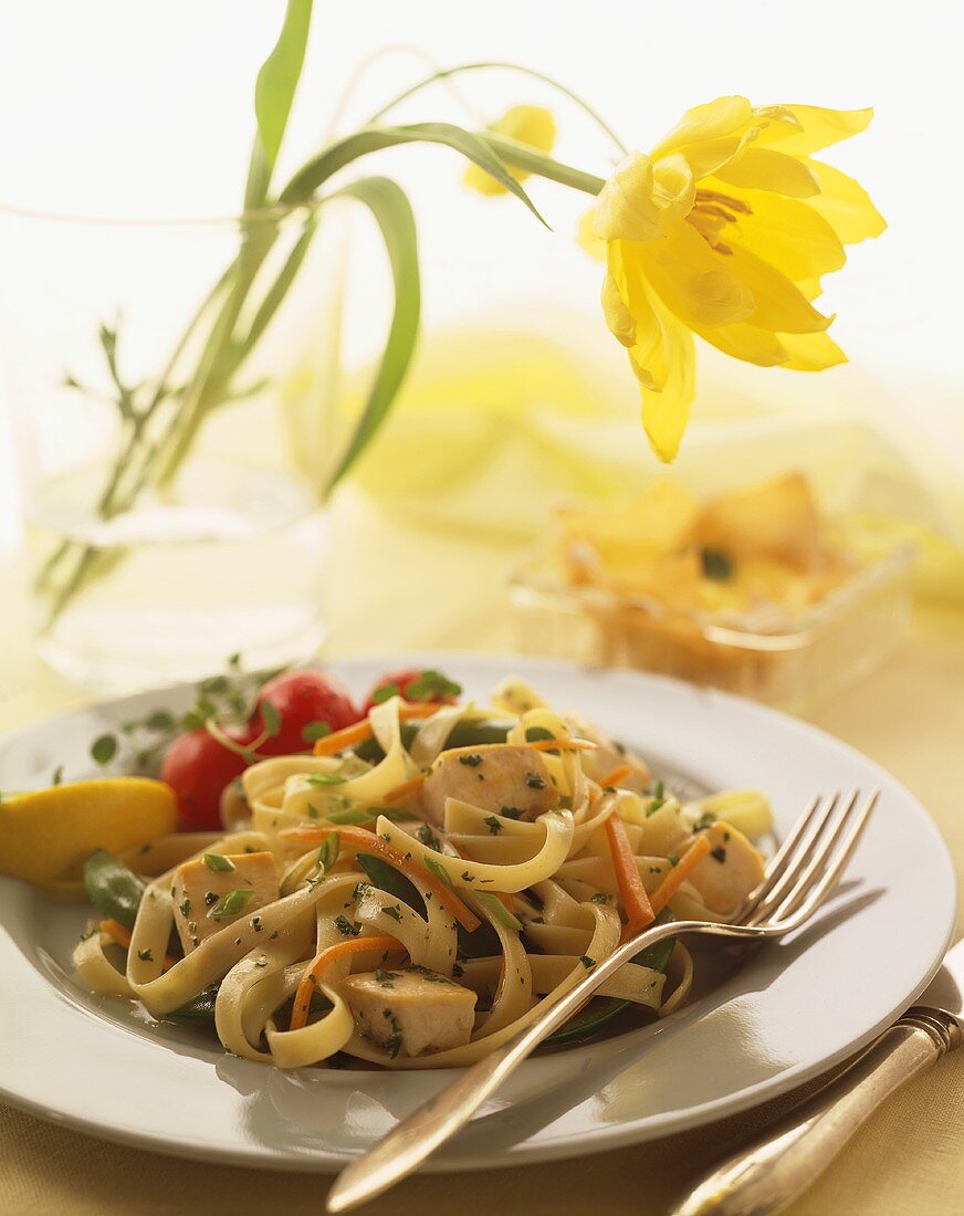 Plate of Fettuccini with Chicken, Carrots and Herbs, Flower in a Vase