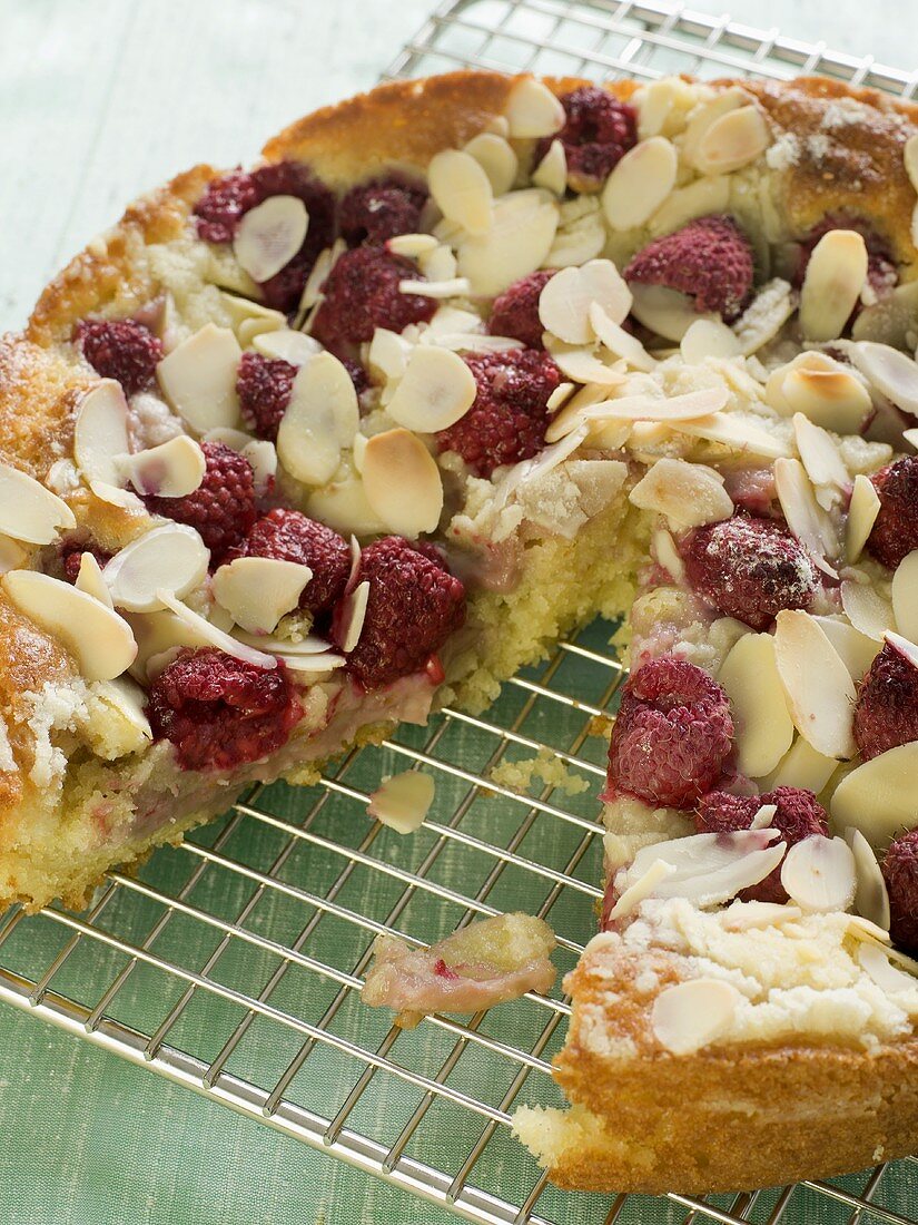 Raspberry Almond Cake with a Slice Removed on Cooling Rack