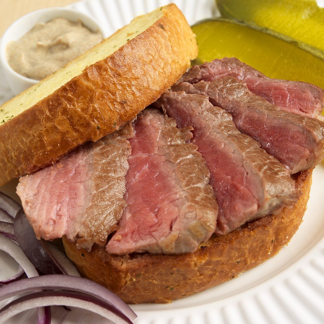 Sliced Rare Steak Sandwich on Texas Toast; Onions and Pickles