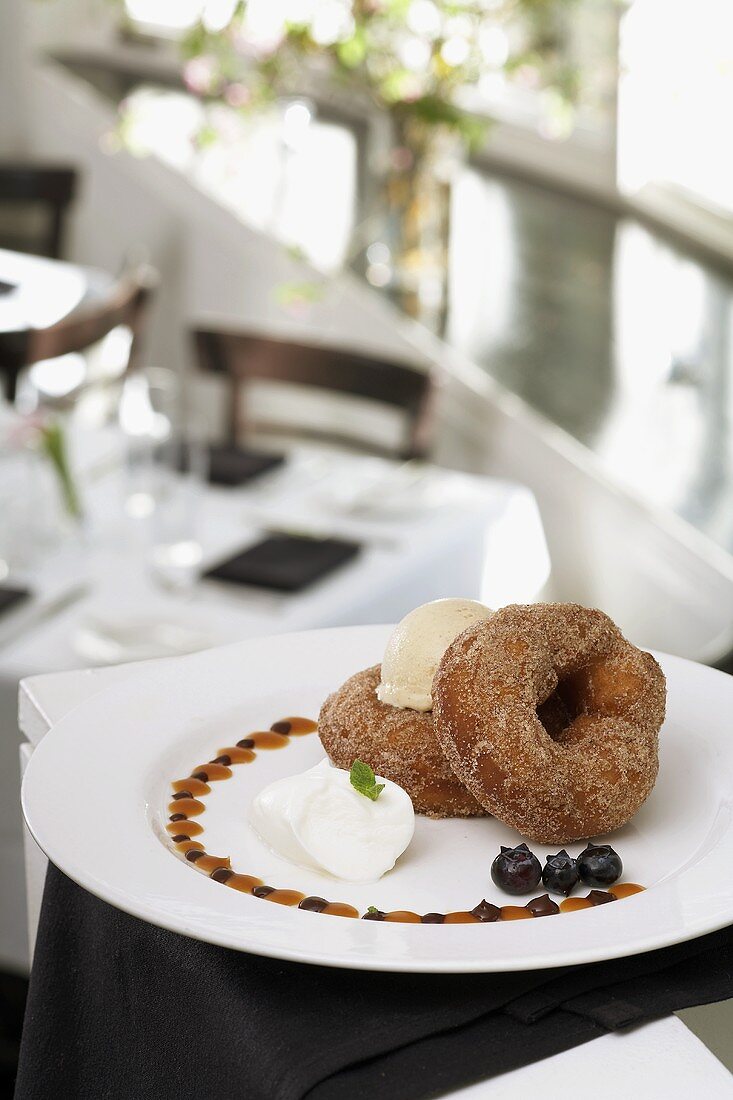 Two cinnamon doughnuts with ice cream on plate in restaurant