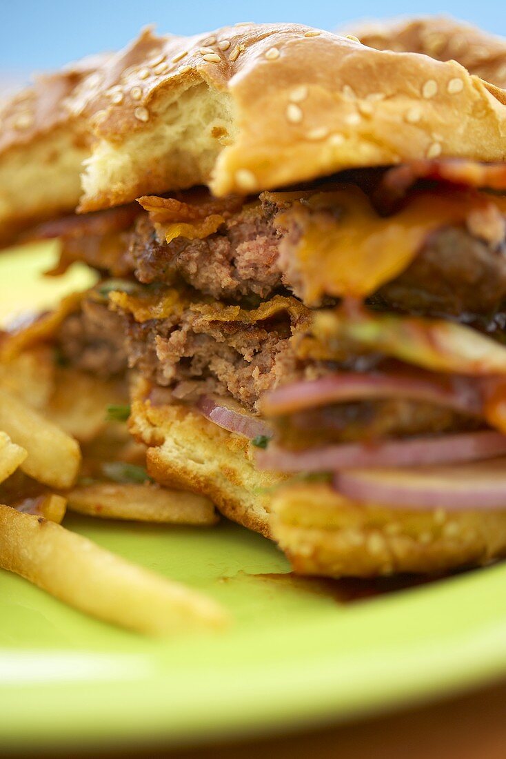 Close Up of Partially Eaten Barbecue Bacon Double Cheeseburger; Fries
