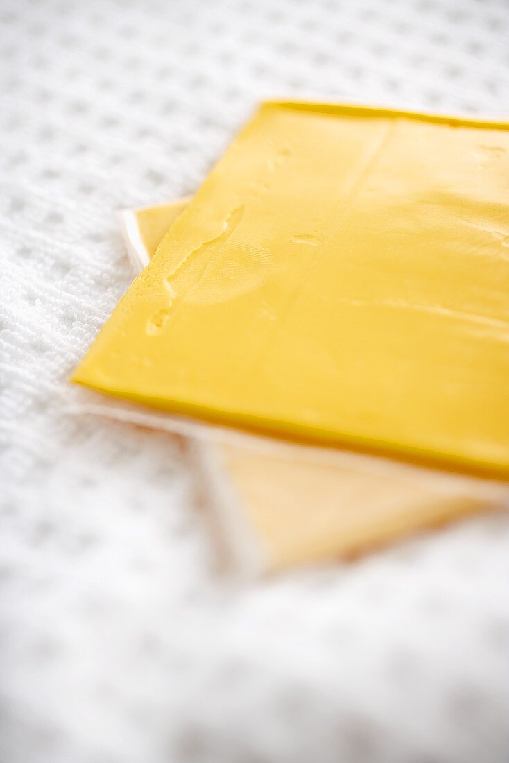 Zwei Scheiben Yellow American Cheese in Plastikfolie