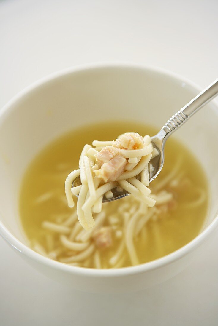 Spoon Scooping Chicken Noodle Soup from a White Bowl