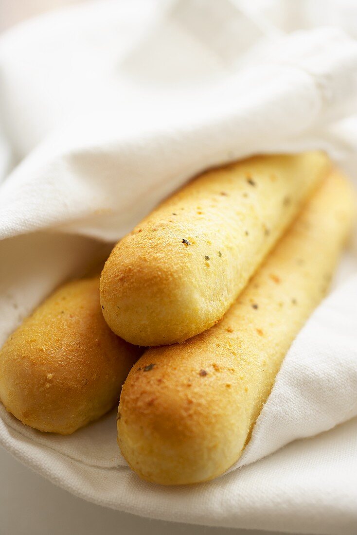 Three Bread Sticks Wrapped in White Linens; Close Up
