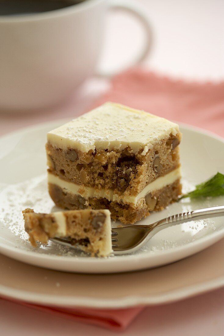 A Piece of Carrot Cake on a Plate; Piece Broken Off with a Fork