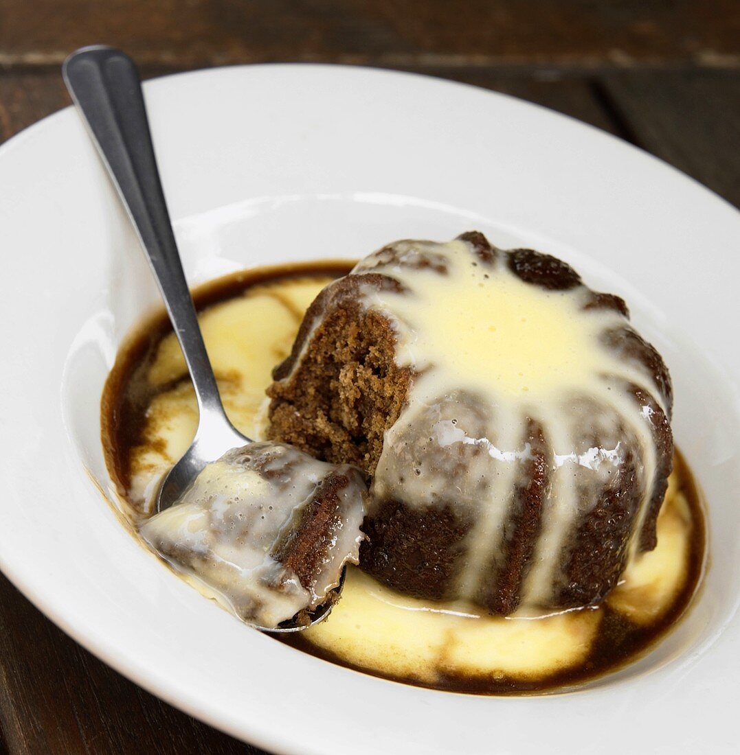 Individual Chocolate Pudding with Custard with a Spoonful Removed