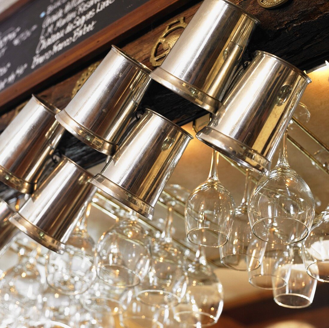 Metal Beer Mugs and Wine Glasses Hanging From a Bar