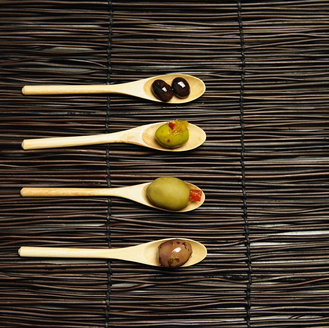 Various Olives on Four Small Wooden Spoons