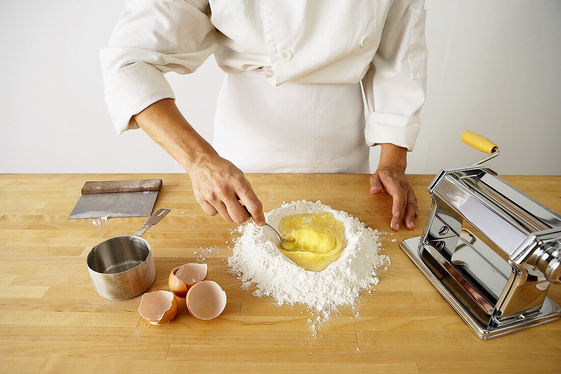 Nudelteig zubereiten: Eier im Mehlhaufen verrühren