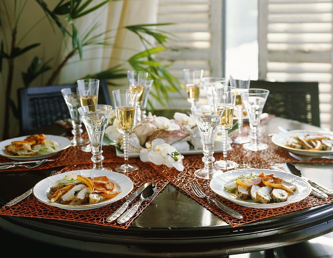 Table Set with Plates of Sliced Stuffed Chicken and White Wine