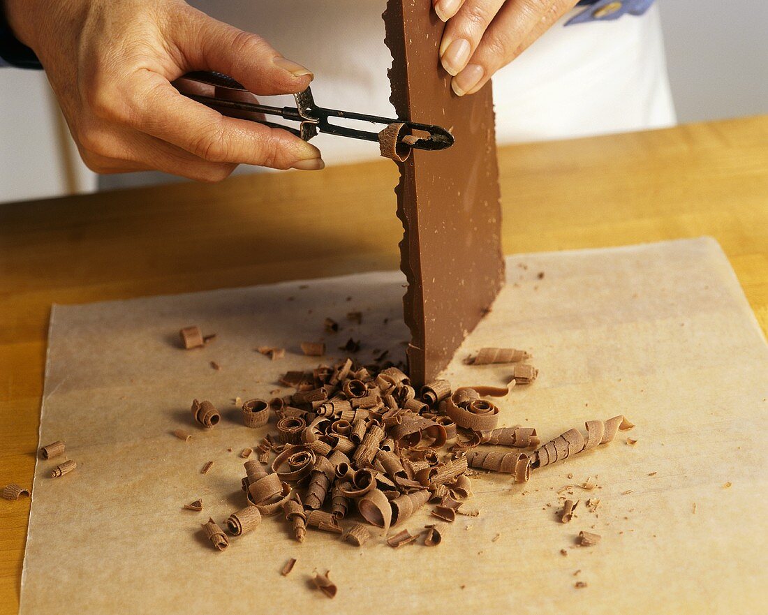Chef Making Chocolate Curls From a Bar of Chocolate with a Peeler
