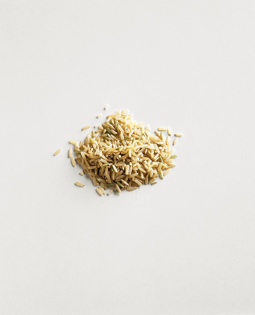 Pile of Uncooked Brown Rice on a White Background