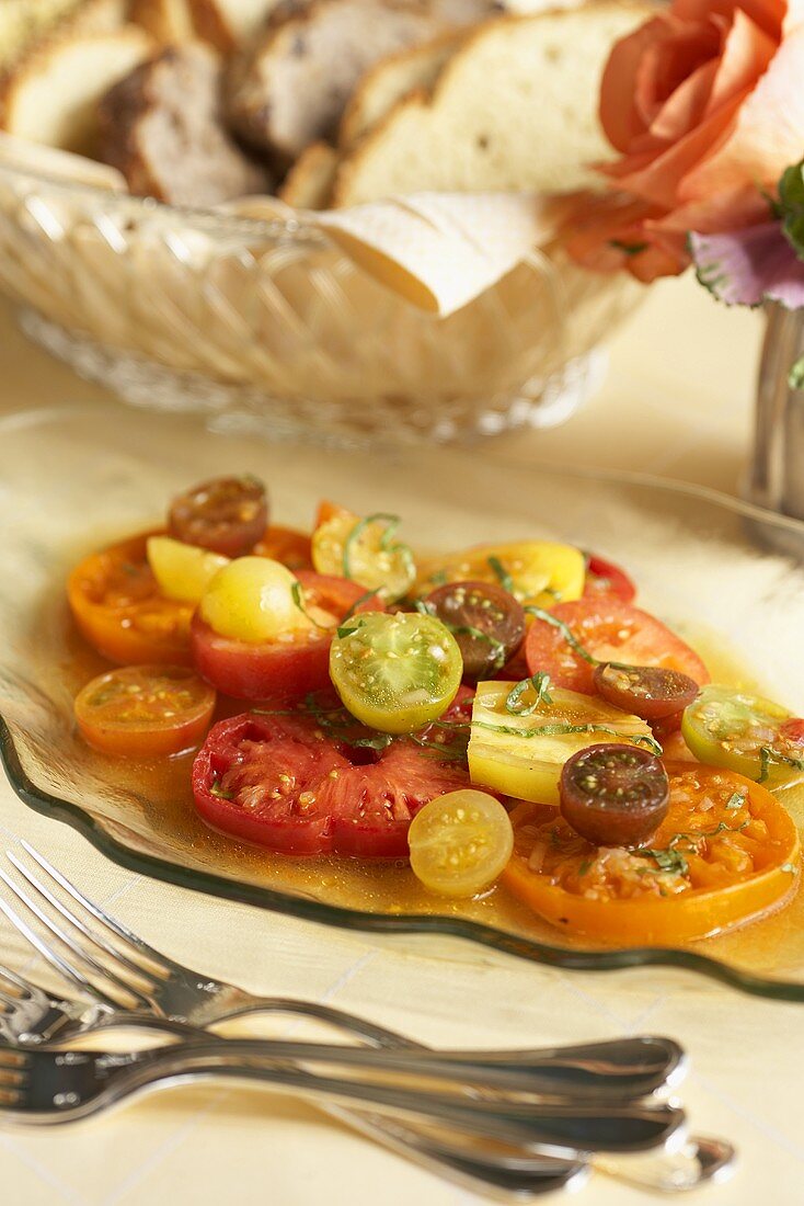 Eine Portion Salat von verschiedenen Tomaten mit Brotkorb